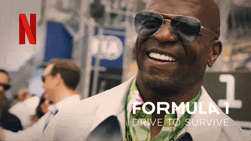 A man wearing sunglasses smiling at an outdoor event with a blurred crowd behind him, overlaid with the Netflix logo and the title "Formula 1: Drive to Survive."