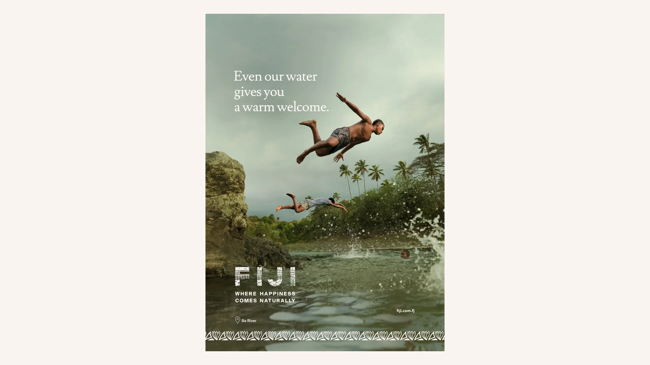 Two people jumping into the water from rocks near a river, with trees and palm trees in the background. Overlay text reads 'Even our water gives you a warm welcome.'