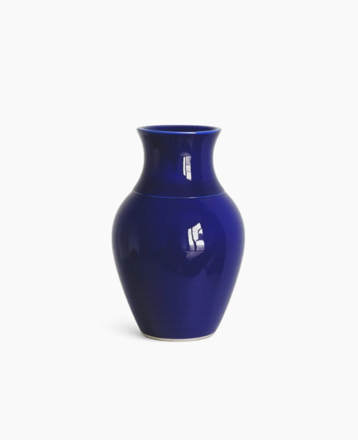 A deep blue ceramic vase with a narrow neck and wider body, reflecting light and a window.