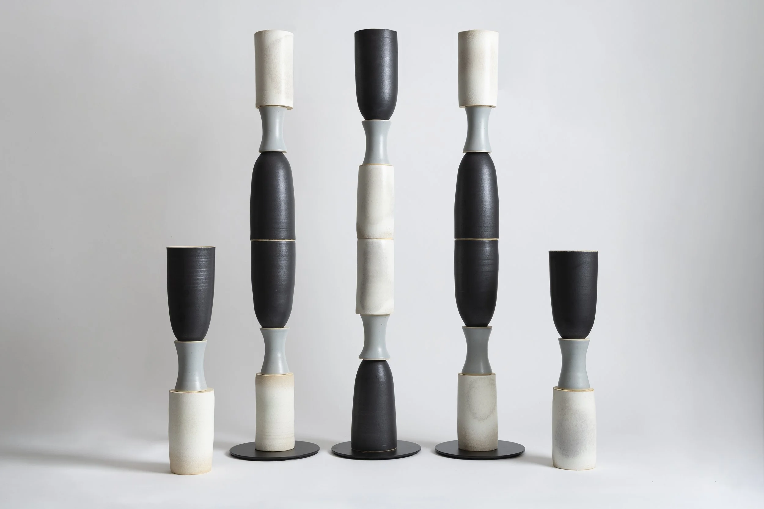 A collection of tall, cylindrical vases with alternating black and white colors, arranged in a symmetrical pattern against a plain light background.