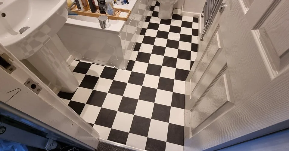 Black and white checkered bathroom floor with a pedestal sink and a small shelf with toiletries.