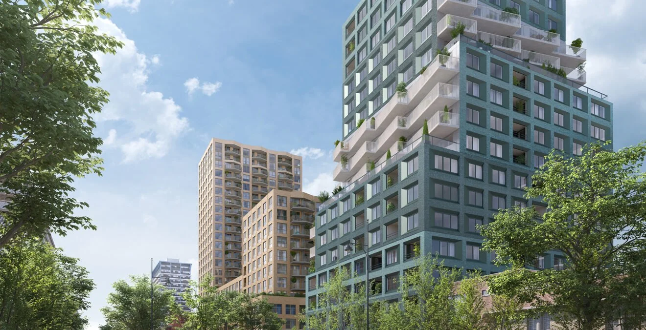 Moderne hoogbouw met veel ramen en balkons, omringd door groene bomen, onder een blauwe lucht met enkele wolken.