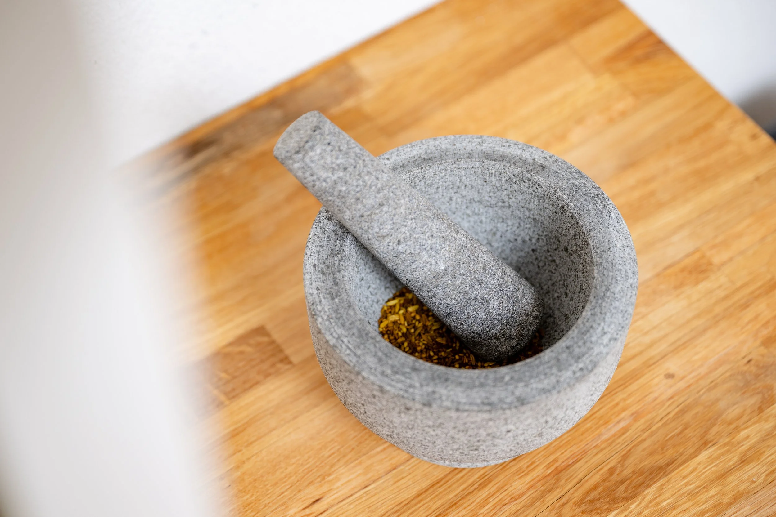 Granitmühle mit gemahlenen Pfefferkörnern auf einem Holztisch