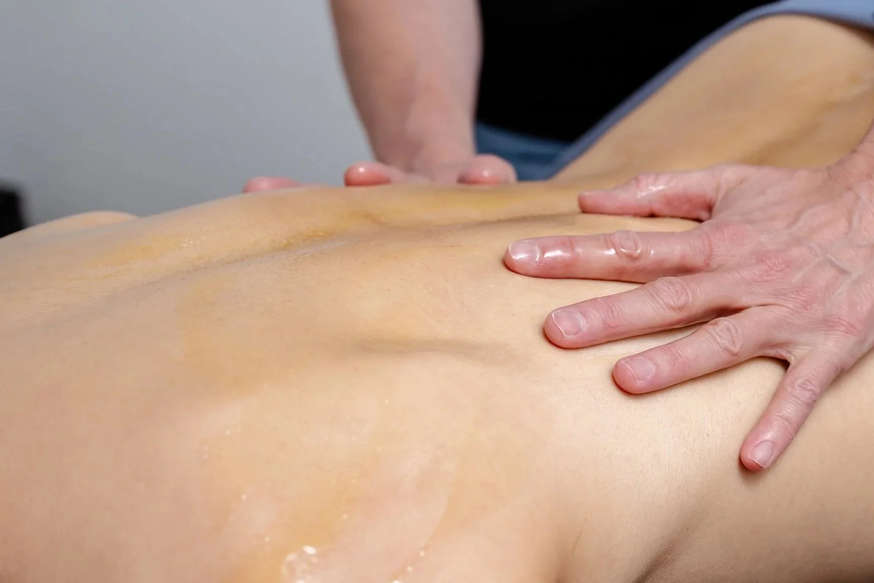 Masseur führt eine Massage an einem Rücken durch.