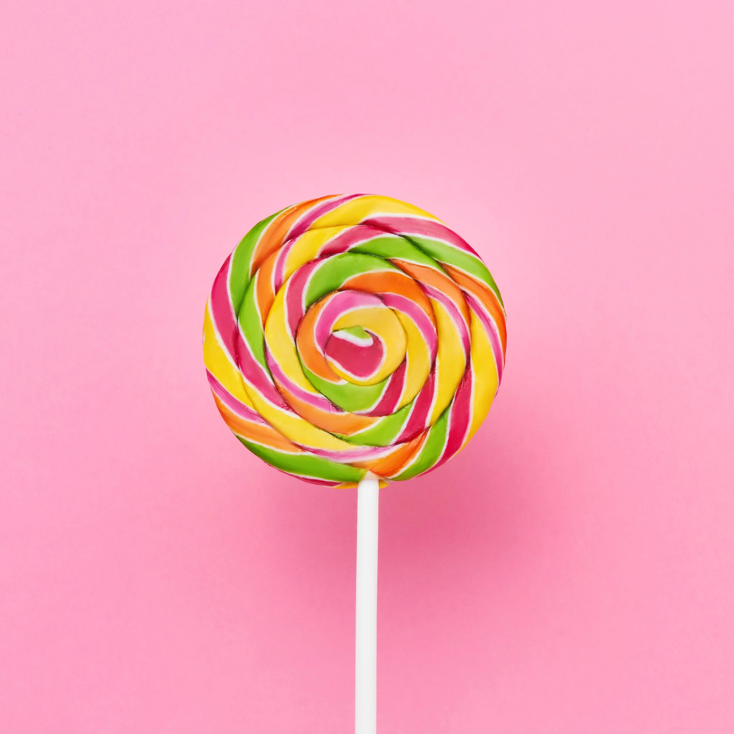 Colorful striped lollipop on a pink background.