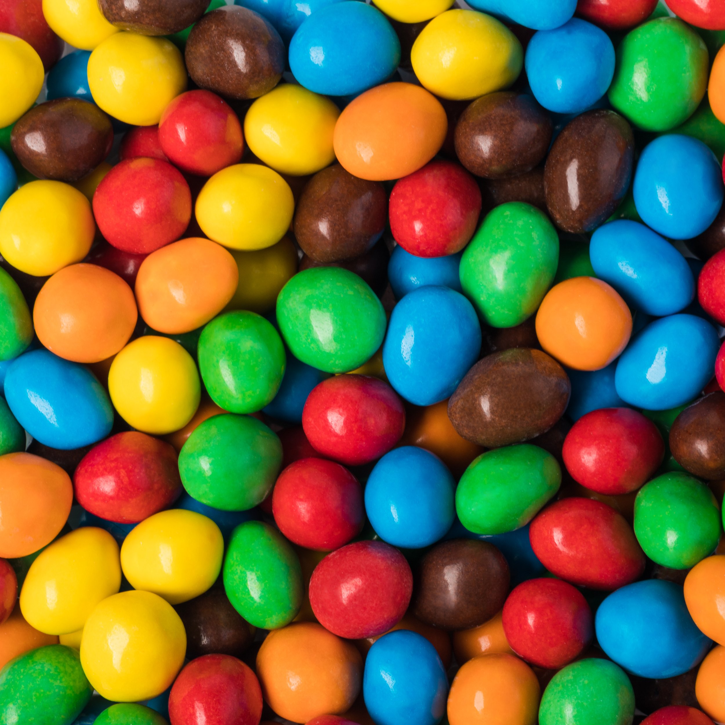 Colorful assorted gumballs in red, yellow, blue, green, orange, and brown with shiny surfaces.