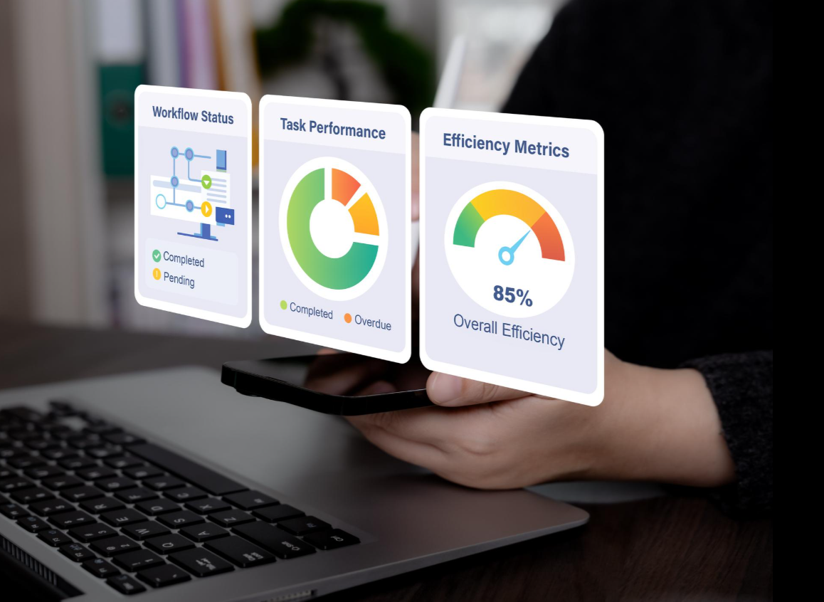 Person holding a smartphone displaying data charts on workflow status, task performance, and efficiency metrics, with a laptop keyboard visible in the foreground.
