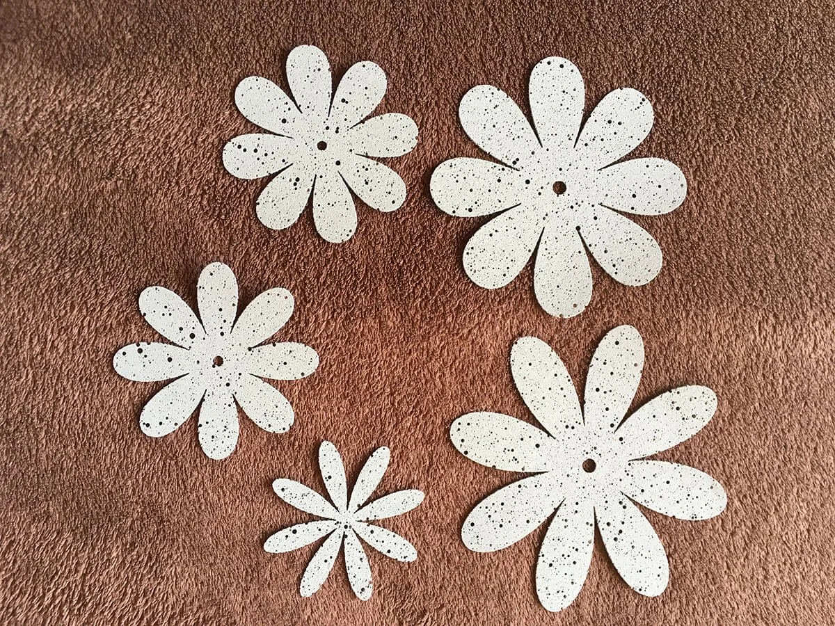 Fünf weiße Schneeflocken in Blütenform auf braunem Untergrund.