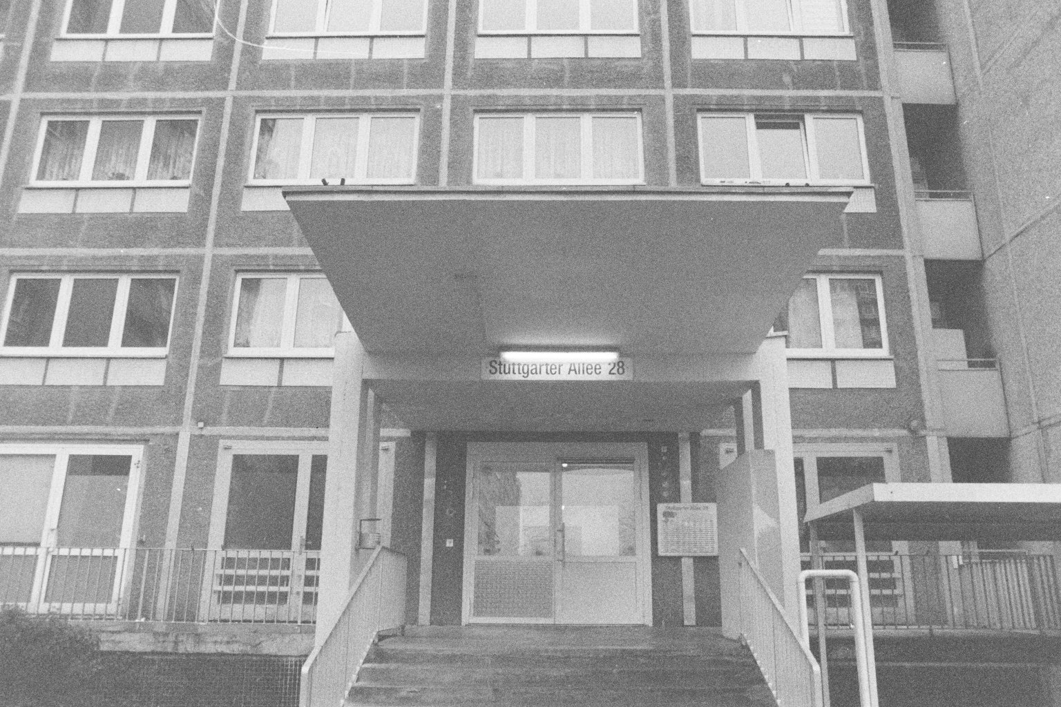 Schwarz-Weiß-Foto eines Mehrfamilienhauses mit Eingang, die Hausnummer ist 28, die Adresse lautet Stuttgarter Allee.