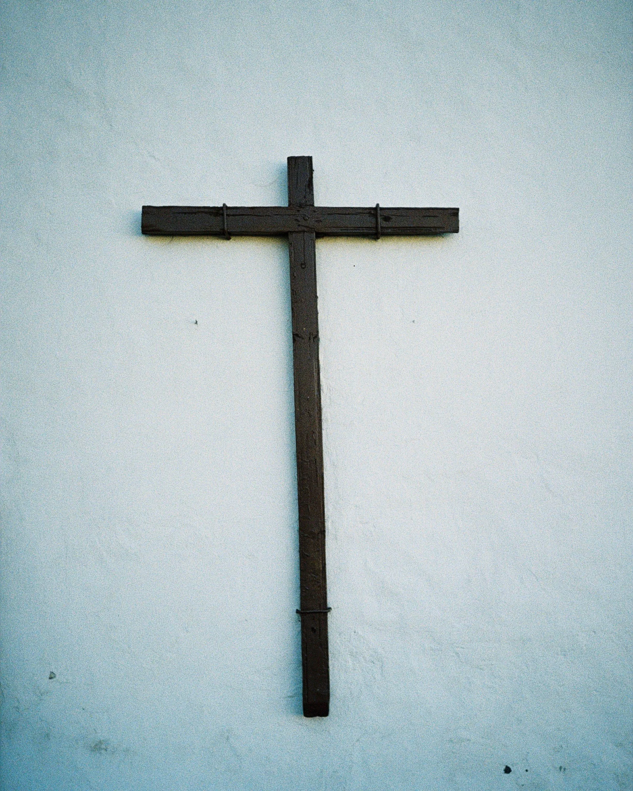 Ein schwarzes Holz-Kreuz auf einer weißen Wand.