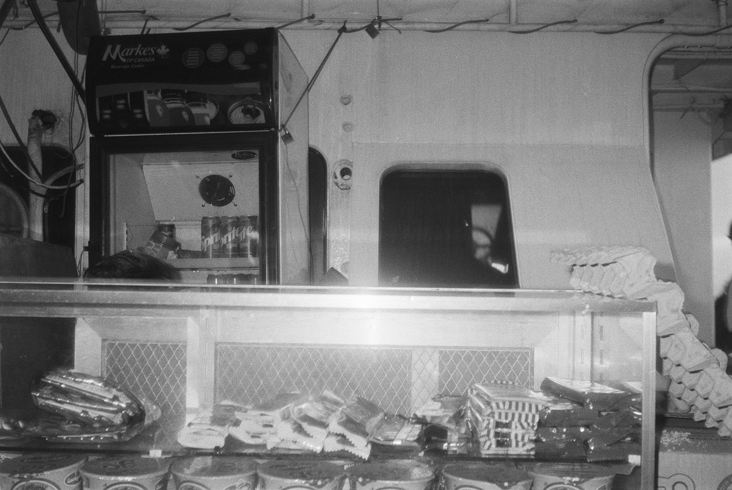 Ein Blick in eine Tiefkühltruhe mit verschiedenen Snacks und Getränken, darunter Chips, Käse, Soßen und Getränkekästen.