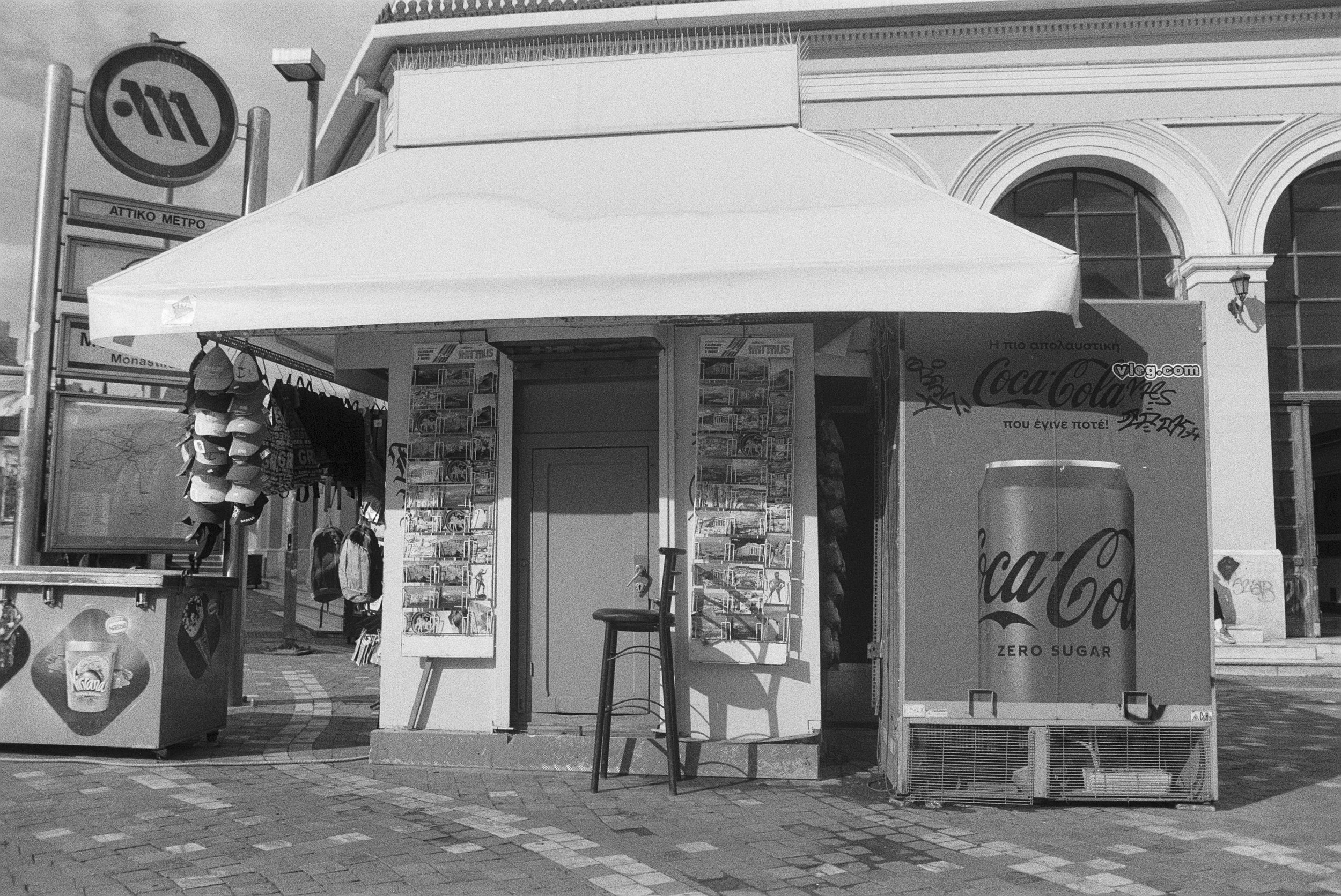 Ein Straßenkiosk, der Getränke verkauft, darunter Cola, mit Graffiti auf der Wand im Hintergrund.