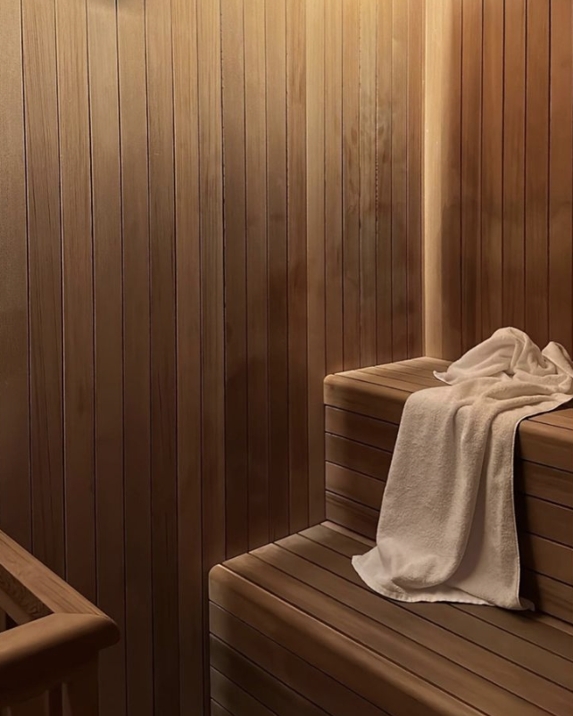 Wood-paneled sauna room with a bench and a towel draped over it.