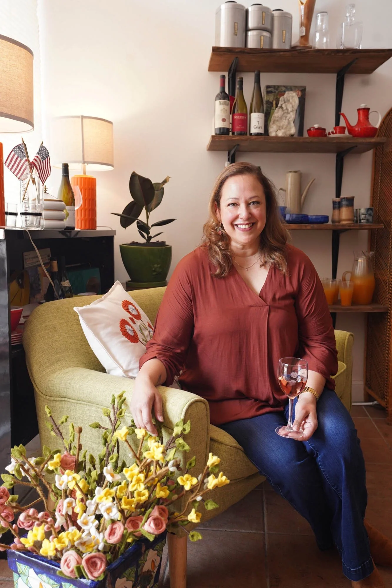 Owner of Kinship Wine + Wares in Northen Virginia sat on green chair holding glass of wine