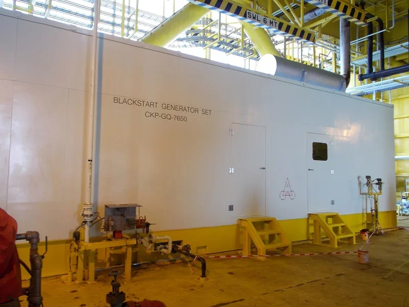 Large industrial generator labeled 'Blackstart Generator Set CKP-GQ-7650' in a factory or power plant, with yellow steps and safety barriers around it.