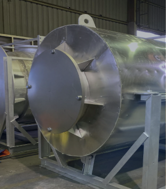 Large industrial metal tank with a rounded front end and support frame inside a warehouse.