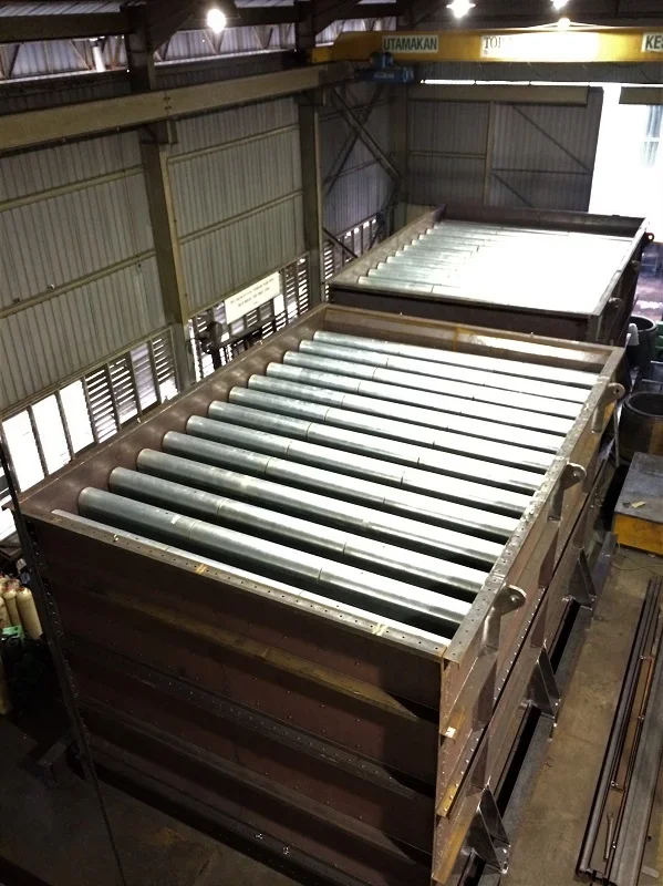 Large industrial roller conveyor inside a warehouse or factory with metal walls and ceiling.