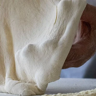 Close-up of pizza dough being stretched.