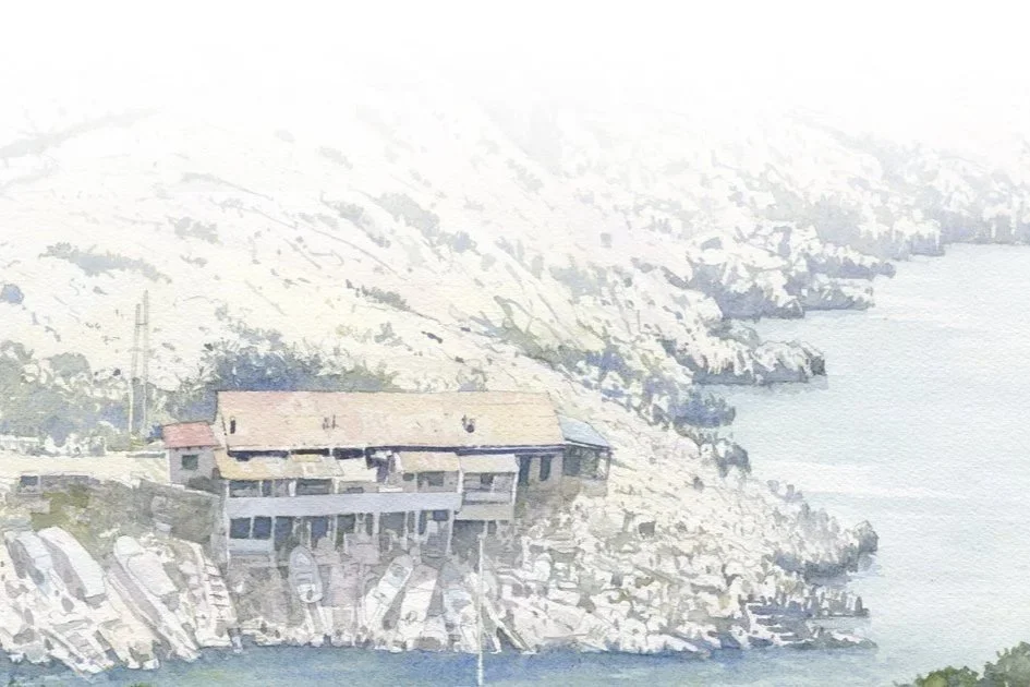 Une maison située sur une falaise rocheuse surplombant la mer, avec un paysage montagneux en arrière-plan.