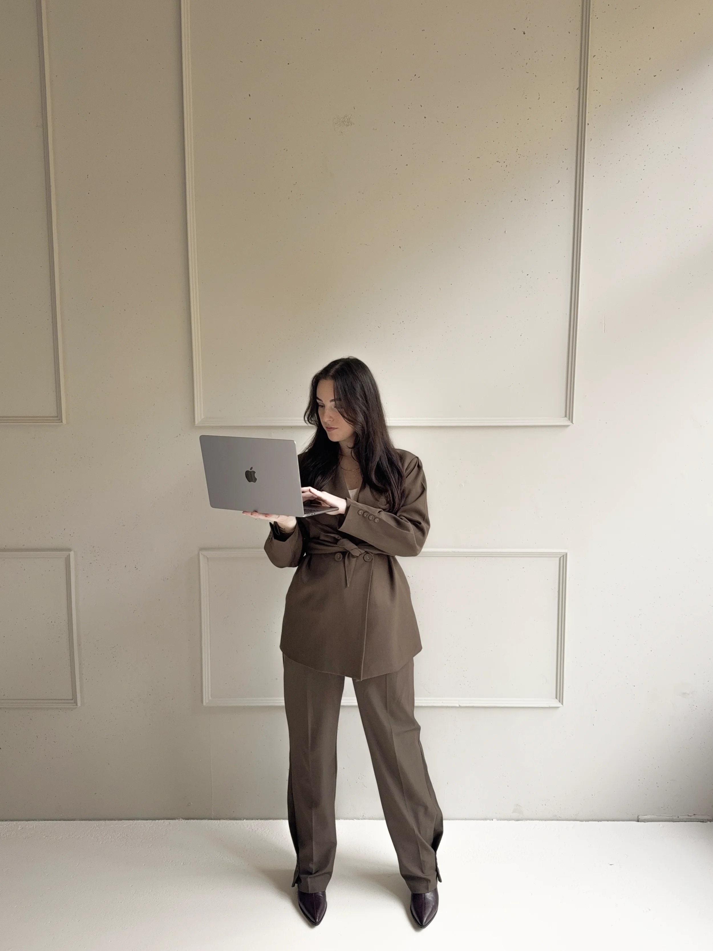 Britt Breemen social media manager, in een bruin pak die naar haar laptop kijkt.