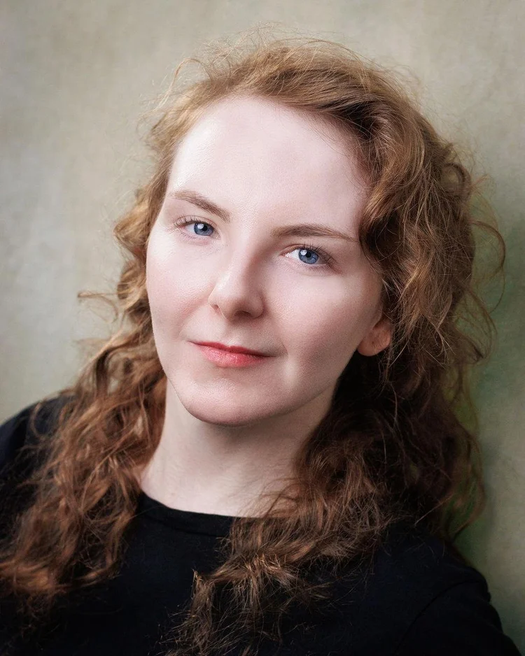 Headshot of actor Elissa Grace in a black top against a muted green background.