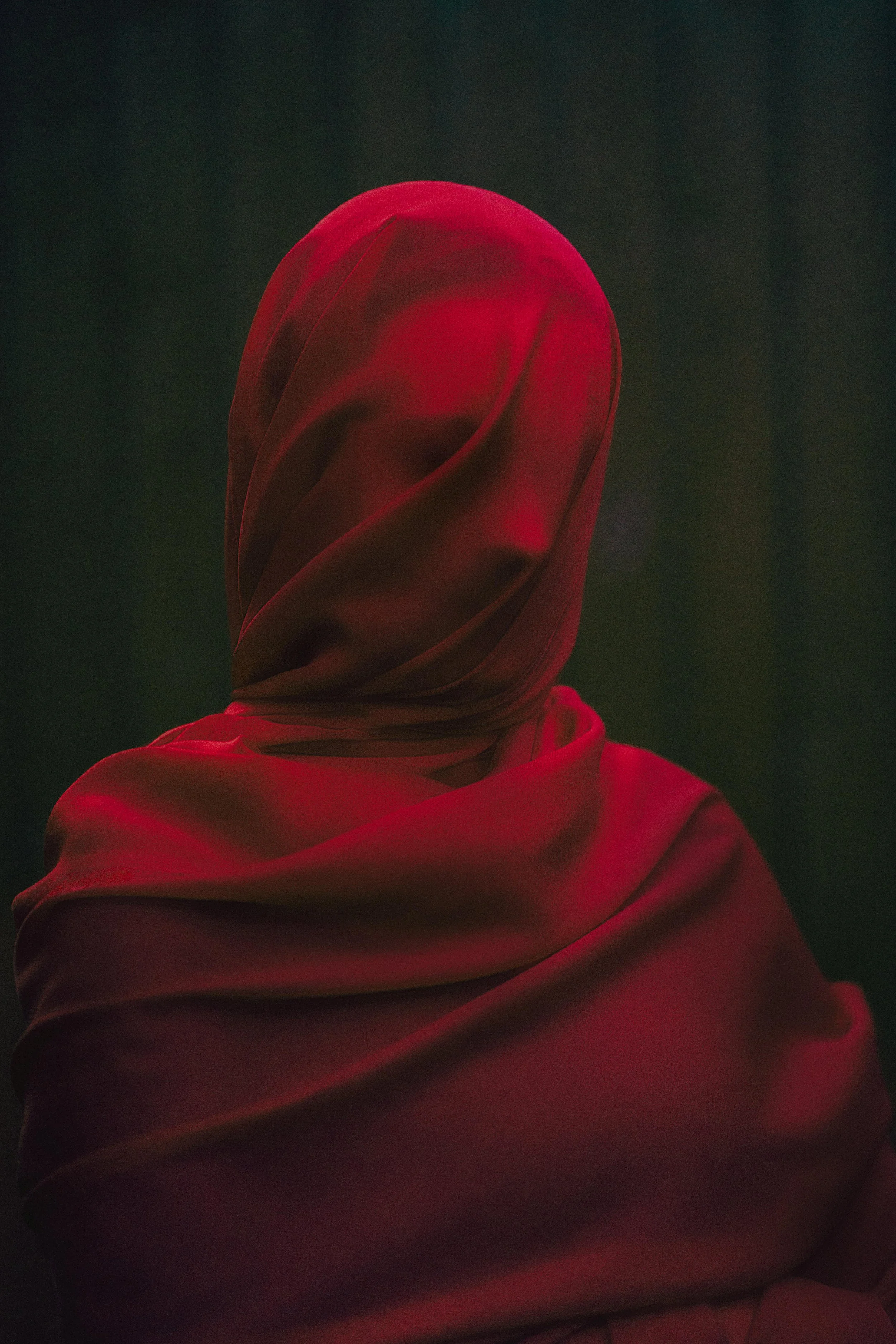 Close-up of a red satin fabric, wrapped and flowing smoothly with reflective highlights.