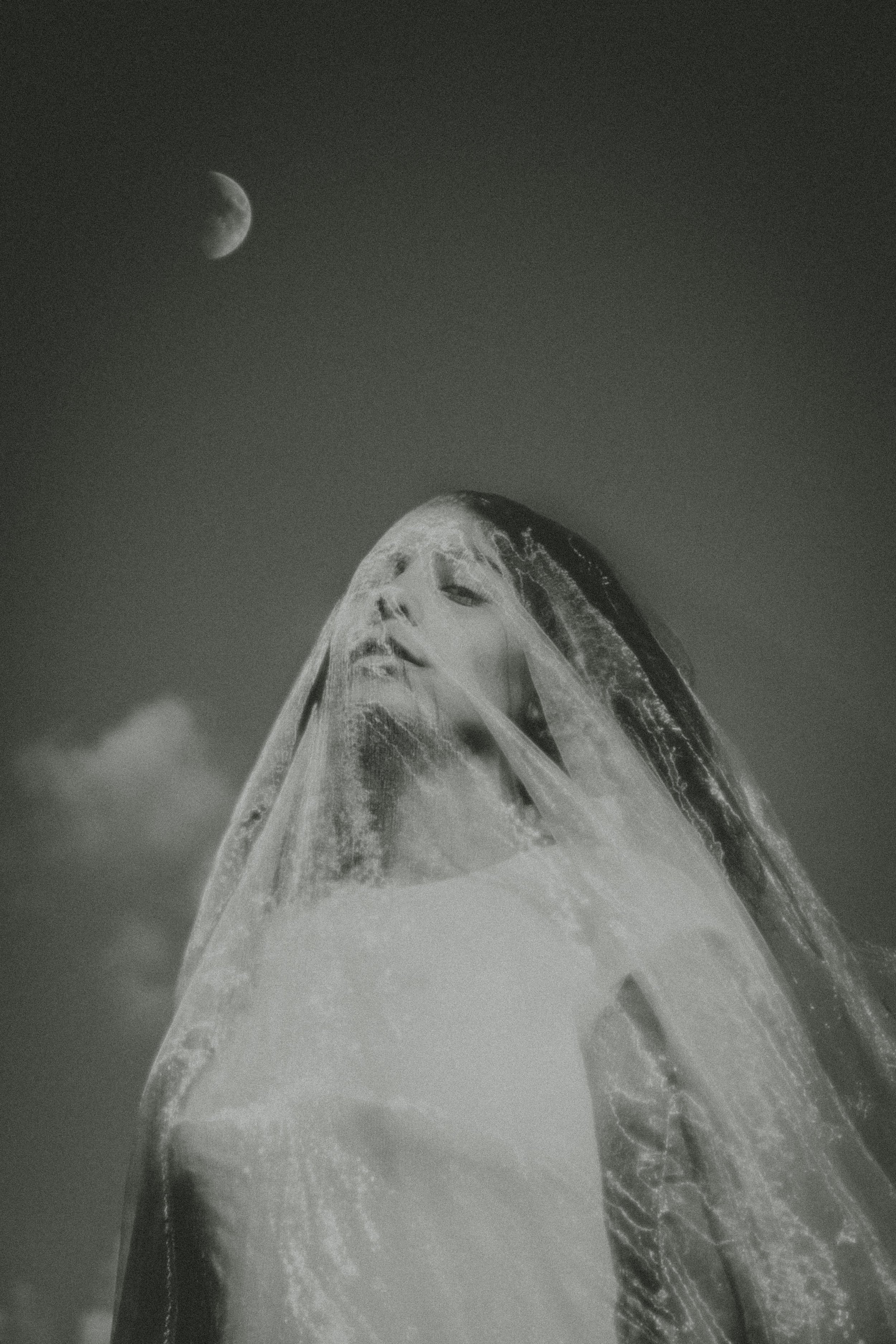 Close-up of an ice sculpture of a woman's face with a moon in the dark sky above.