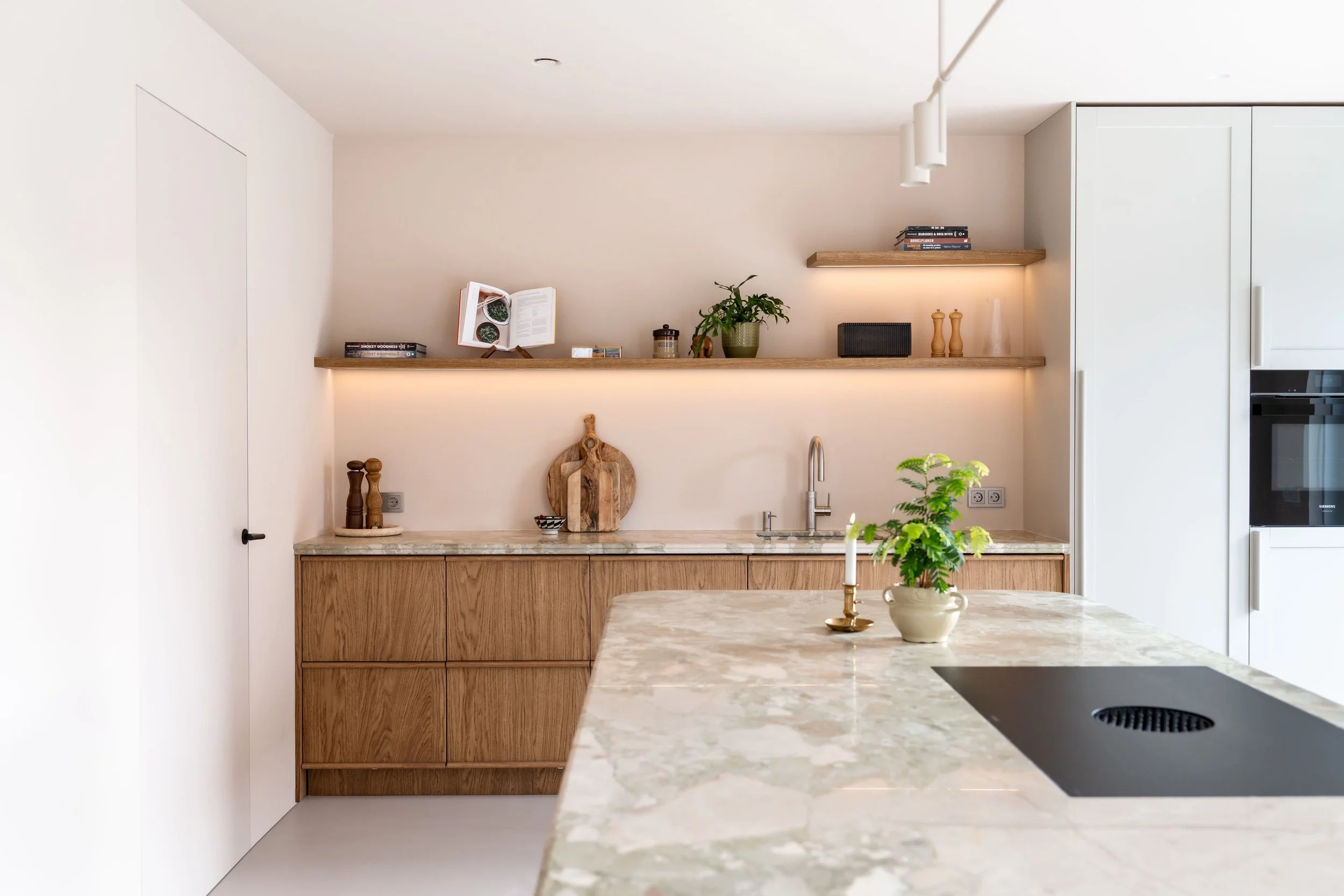 Maatwerk keuken van eiken fineer met natuurstenen werkblad en warme natuurlijke uitstraling.