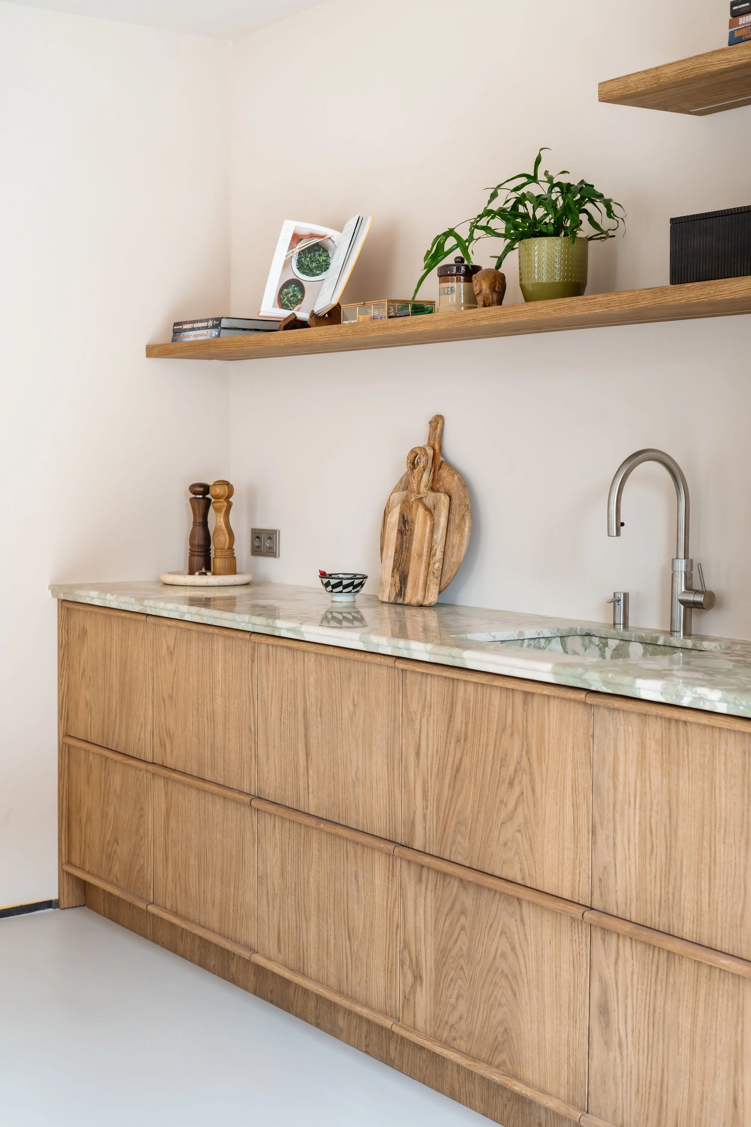 Maatwerk keuken van eiken fineer met natuurstenen werkblad, Quooker kraan en geïntegreerde houten handgrepen.