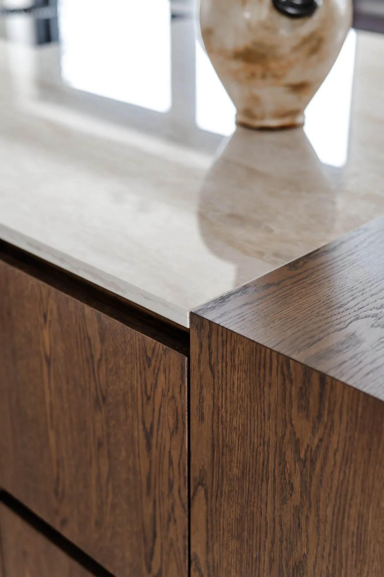 Detail van een maatwerk keuken met donker eiken fineer en Dekton werkblad.