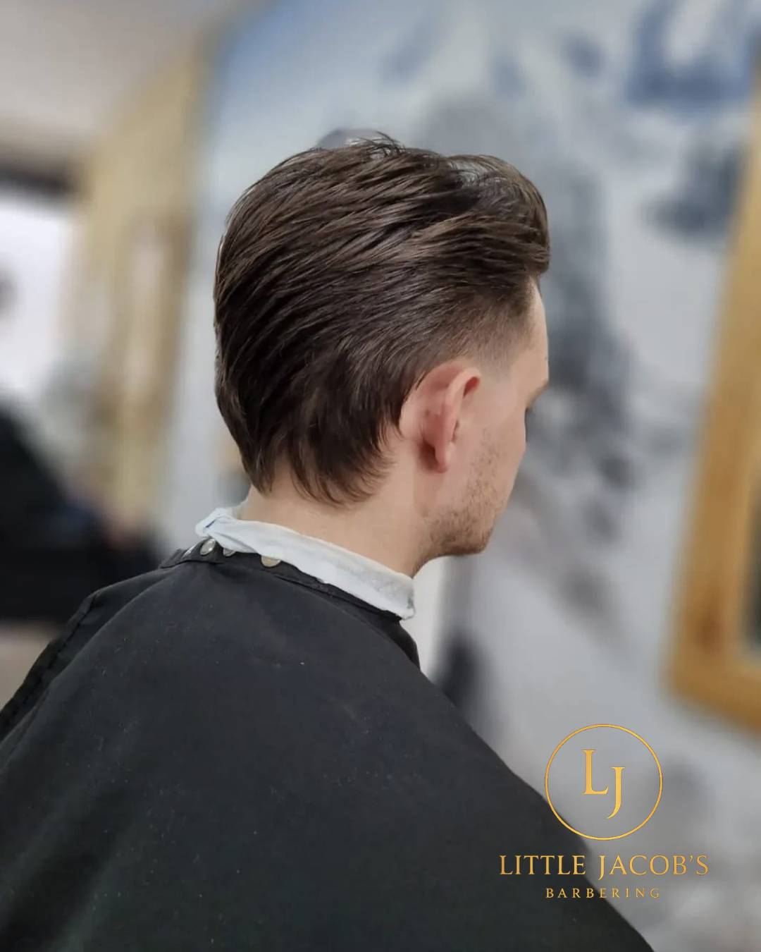 Side profile of a man in a barber shop with a fresh, slicked-back haircut.