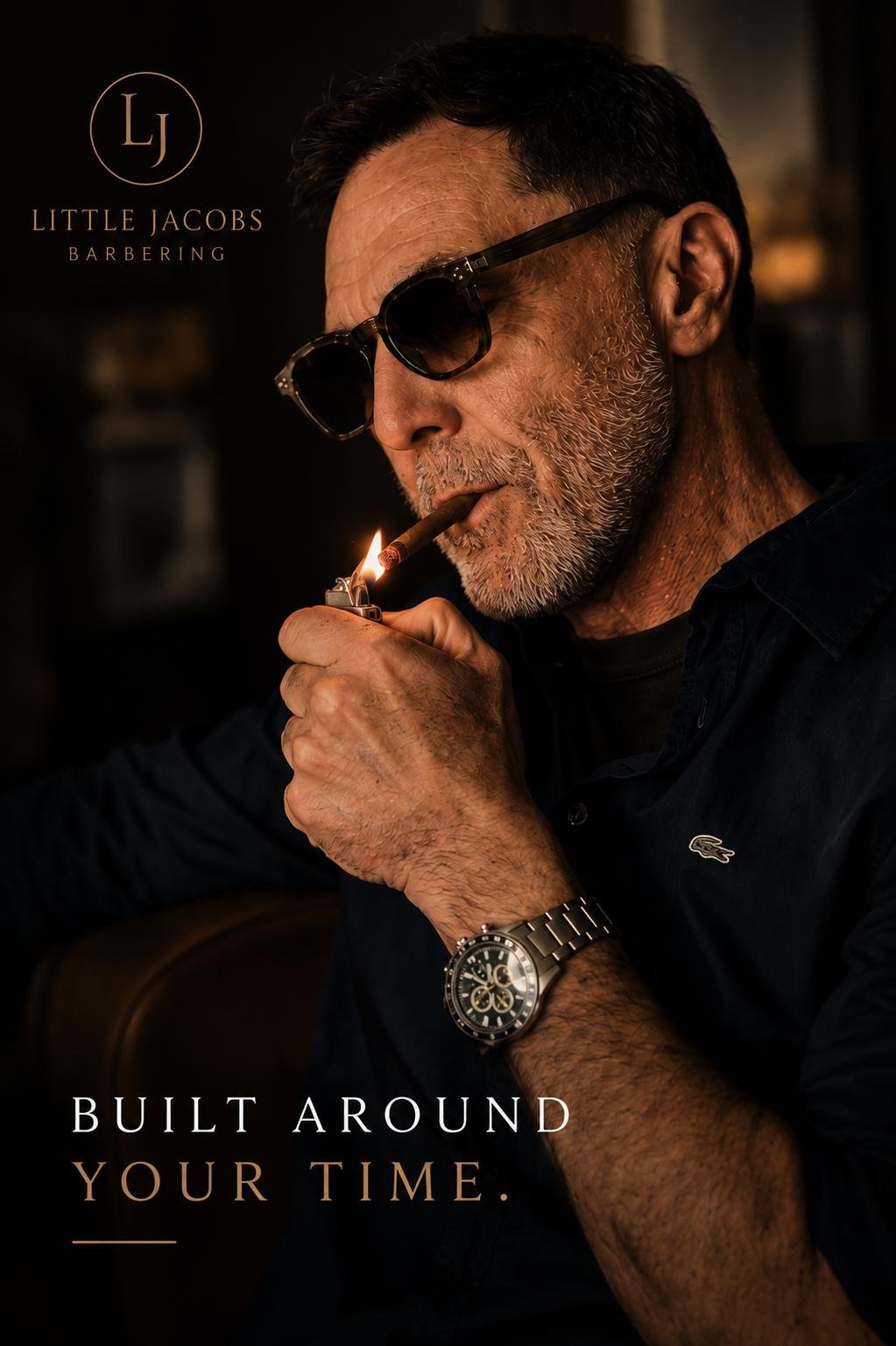 An older man with gray hair and beard, wearing sunglasses and a dark Lacoste shirt, lighting a cigar with a lighter. He has a watch on his wrist and is in a dimly lit setting. The image includes the logo 'LJ' and the text 'Little Jacobs Barbering' al