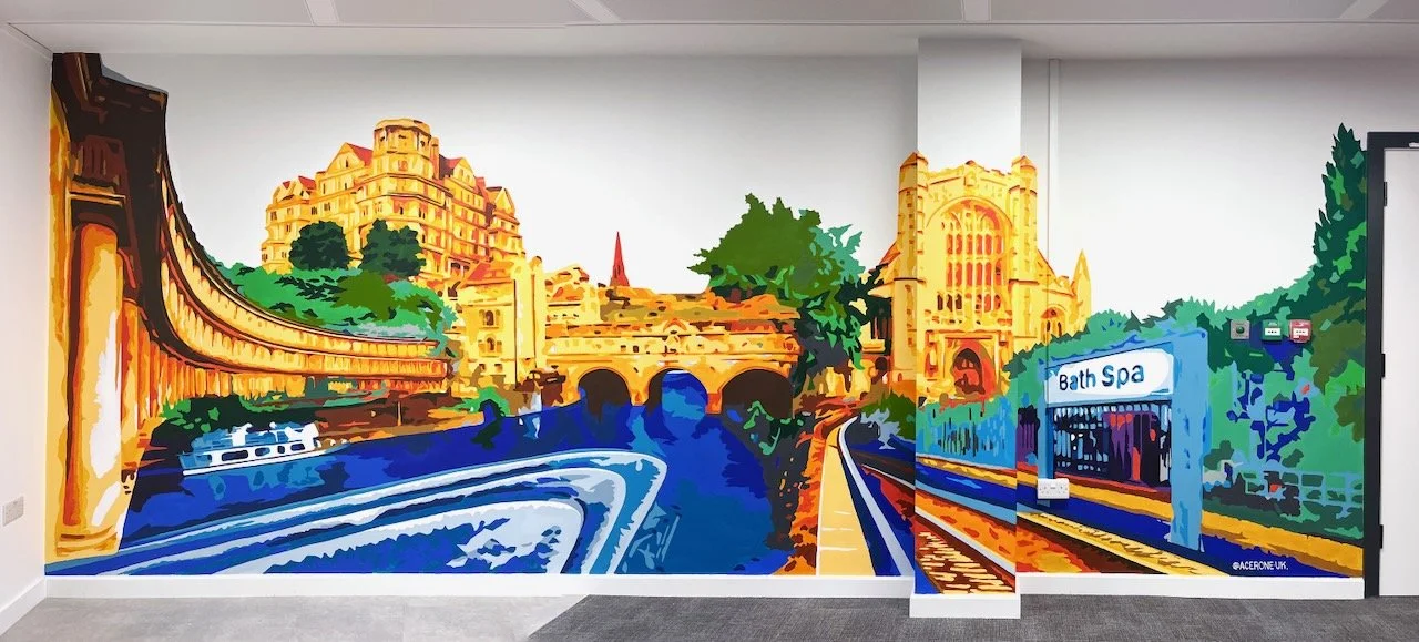 Colorful mural depicting a cityscape with buildings, a bridge, water, rail tracks, trees, and a Bath Spa sign.