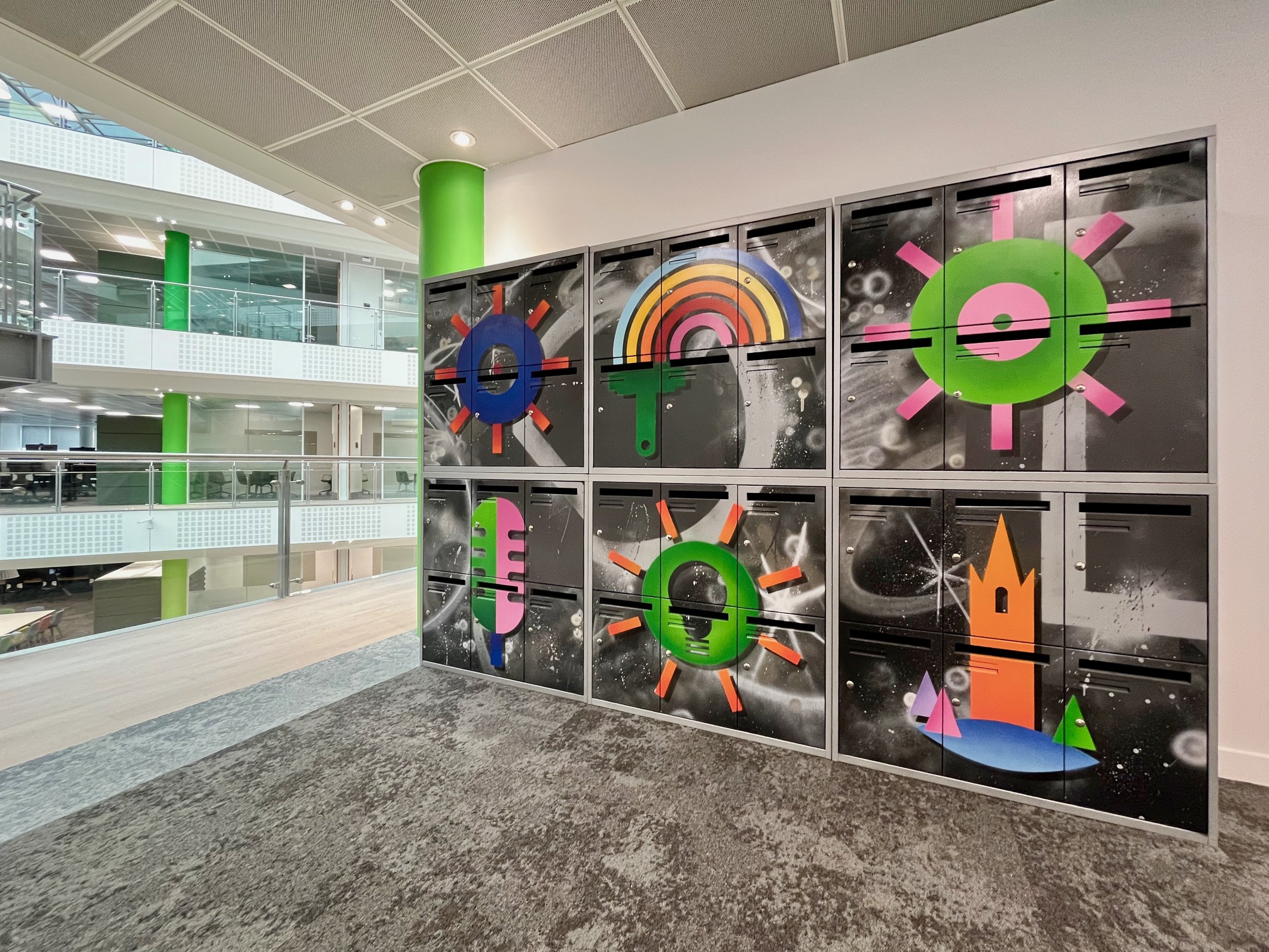 Colorful lockers with abstract, geometric artwork in an office or lobby space.
