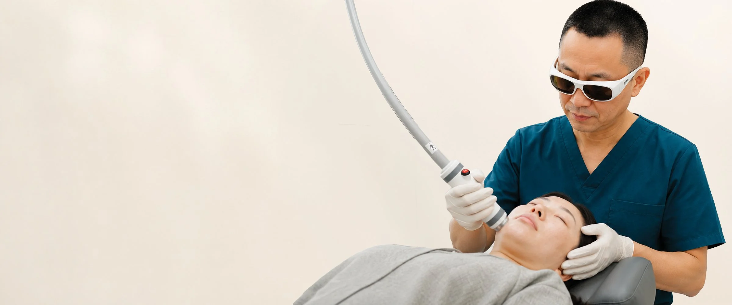 Medical professional performing a laser treatment on a female patient lying on a treatment chair, wearing protective eyewear.