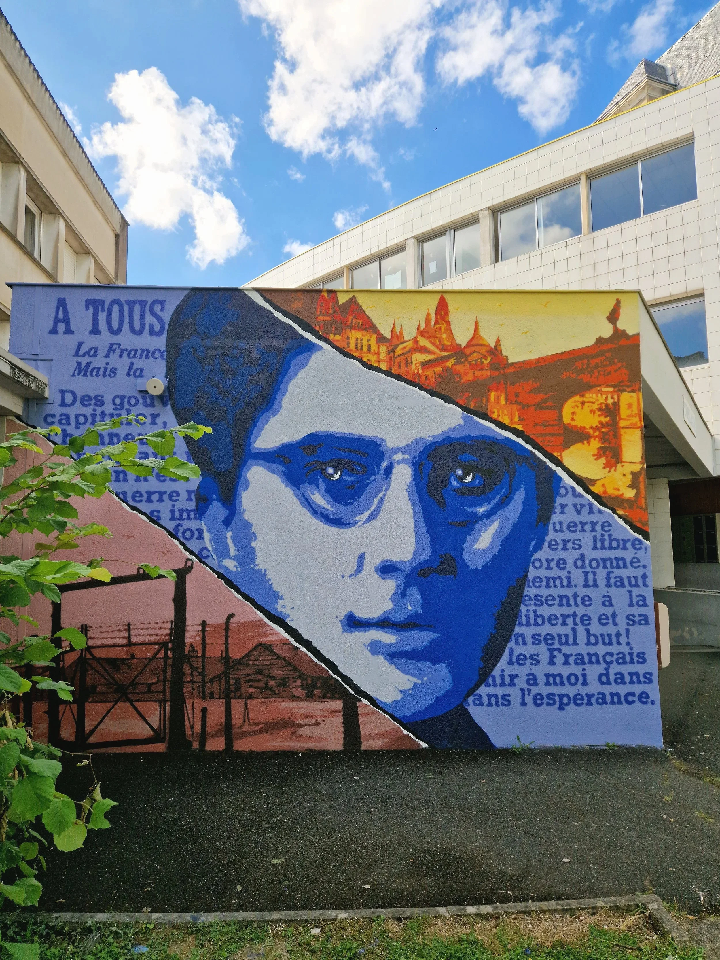 Un mur avec une fresque représentant un visage en style artistique, avec des textes en français et une image de paysage en arrière-plan.