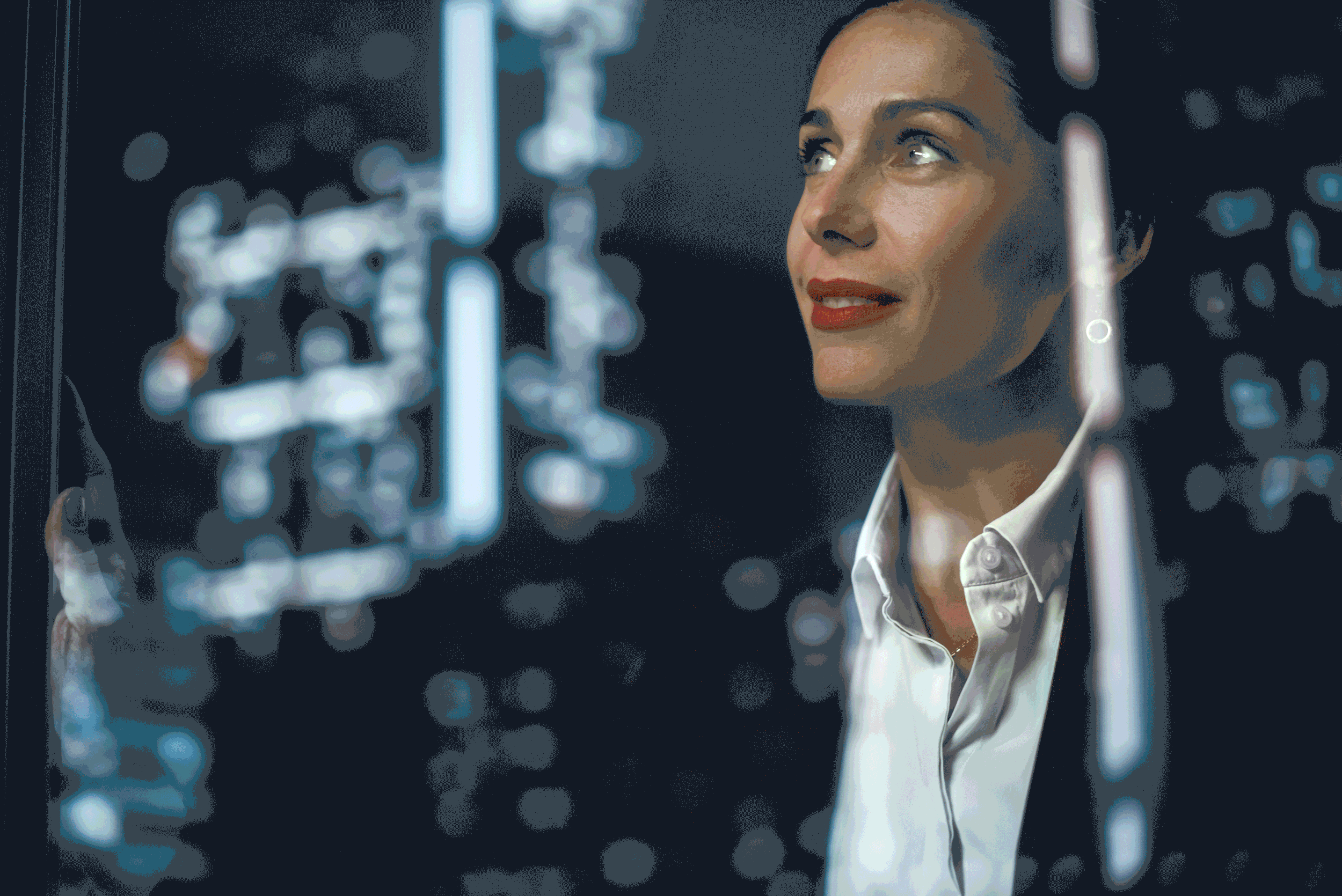 Citris. A woman with short dark hair, wearing a white shirt, is looking at a model of a DNA double helix in a laboratory.
