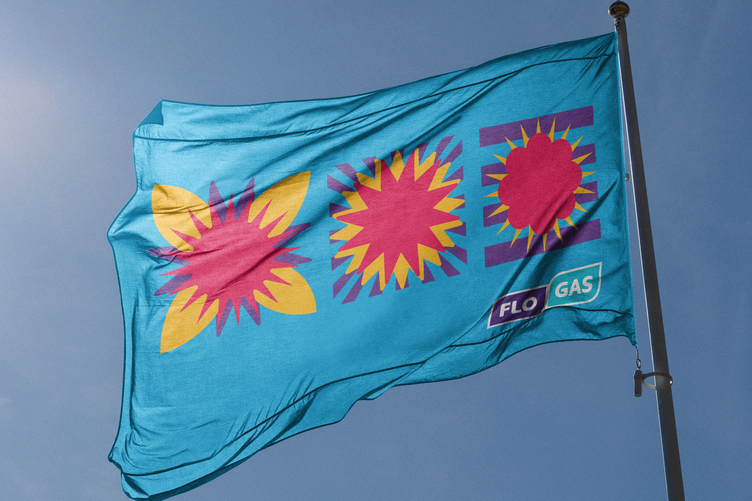 Flogas at Electric Picnic. Blue flag with colorful floral and geometric patterns, attached to a flagpole against a blue sky.