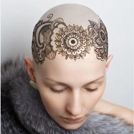 A bald woman with henna-style black and brown decorative designs on her scalp, closed eyes, and wearing a gray fur garment.