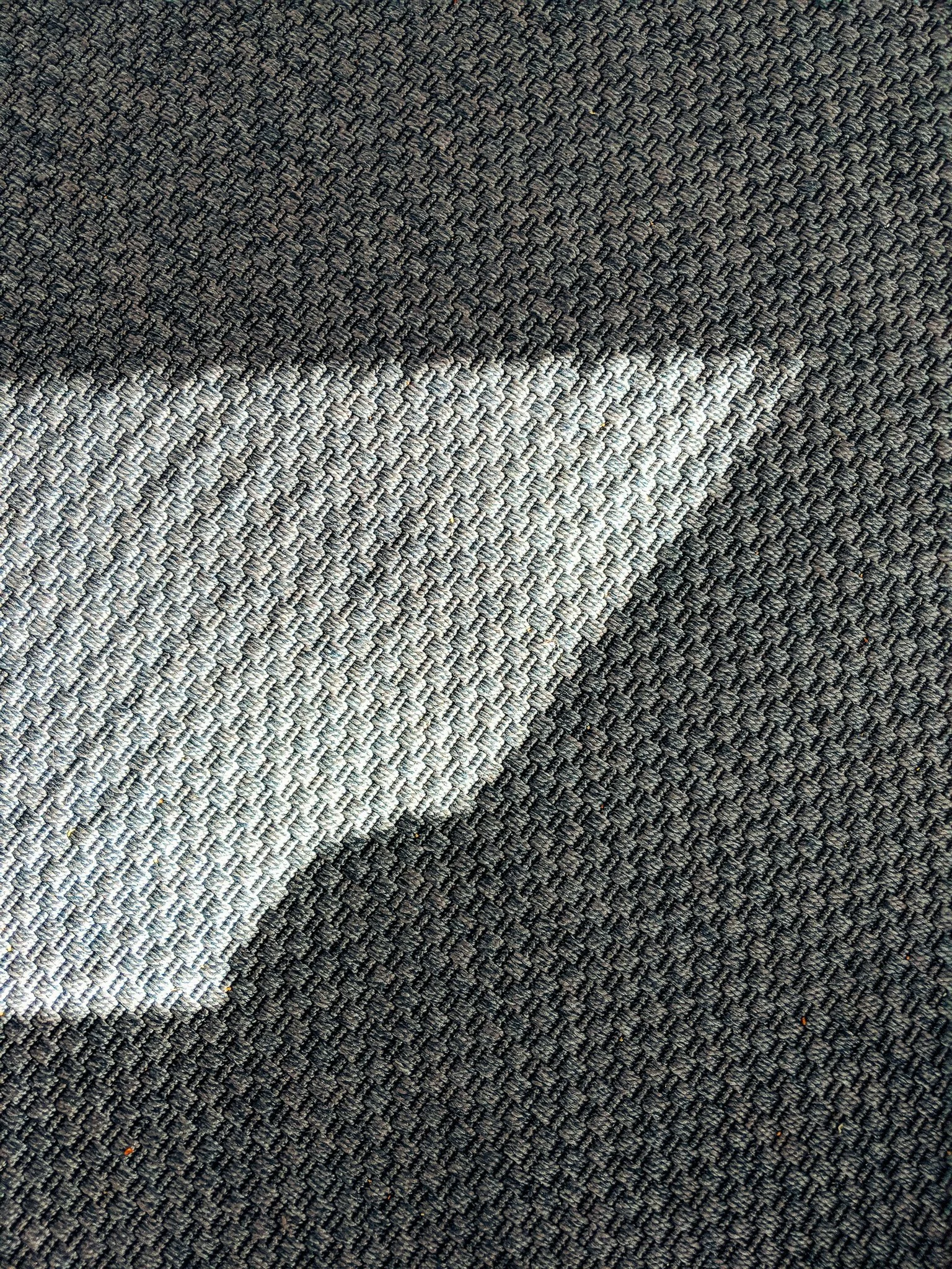 Close-up view of a dark gray textured carpet with small, closely knit loops.