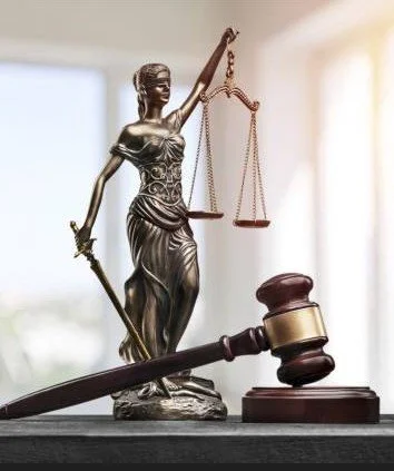Statue of Lady Justice holding scales and a sword, with a gavel in front.