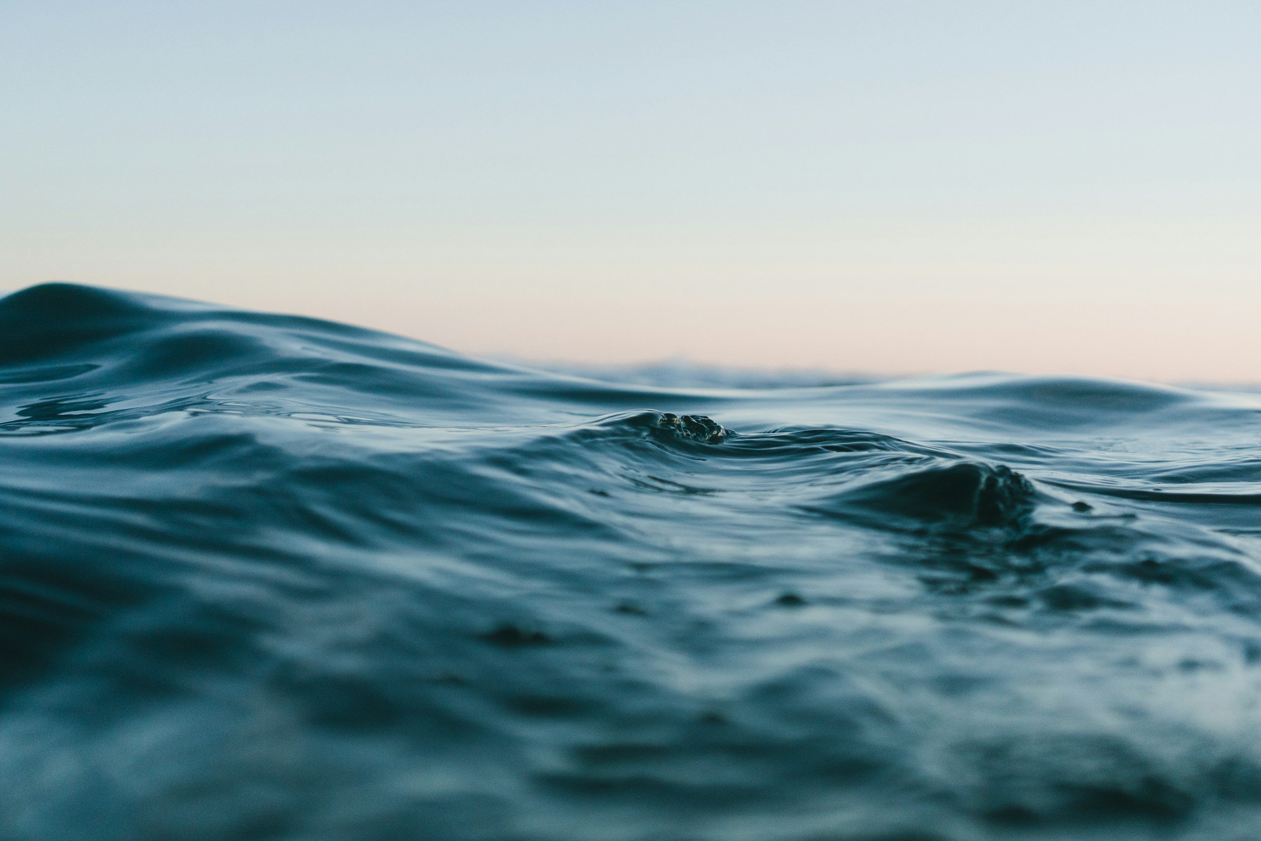 Close-up of calm ocean waves with a gradient sky in the background.