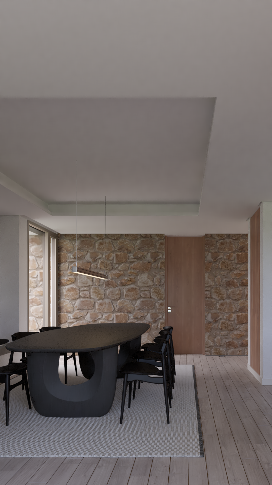 Sala de comedor moderna con pared de piedra, mesa negra con forma ovalada y sillas negras, lámpara suspendida y puerta de madera, con piso de madera y alfombra gris.