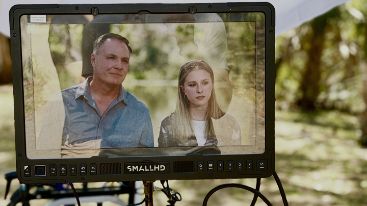 Film director's monitor showing a scene with a man and a young girl outdoors.