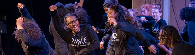 A group of young girls dancing and smiling during a performance or dance class.
