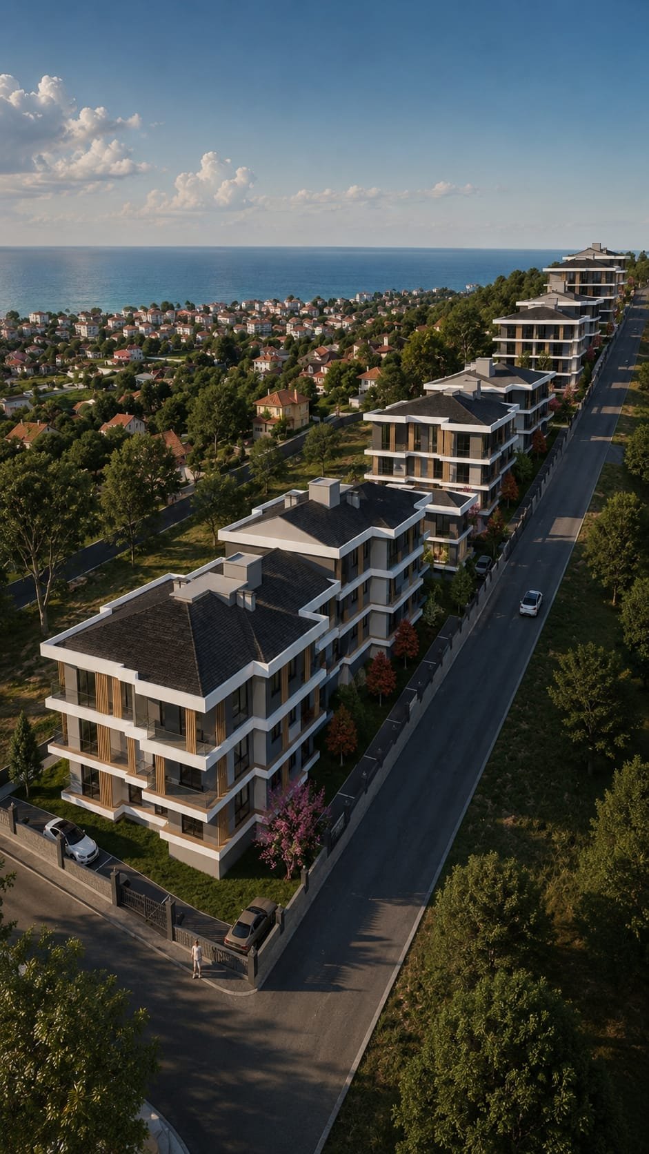 Deniz manzaralı yeni inşa edilen apartmanlar ve arka planda küçük evler ile yeşil alanlar.