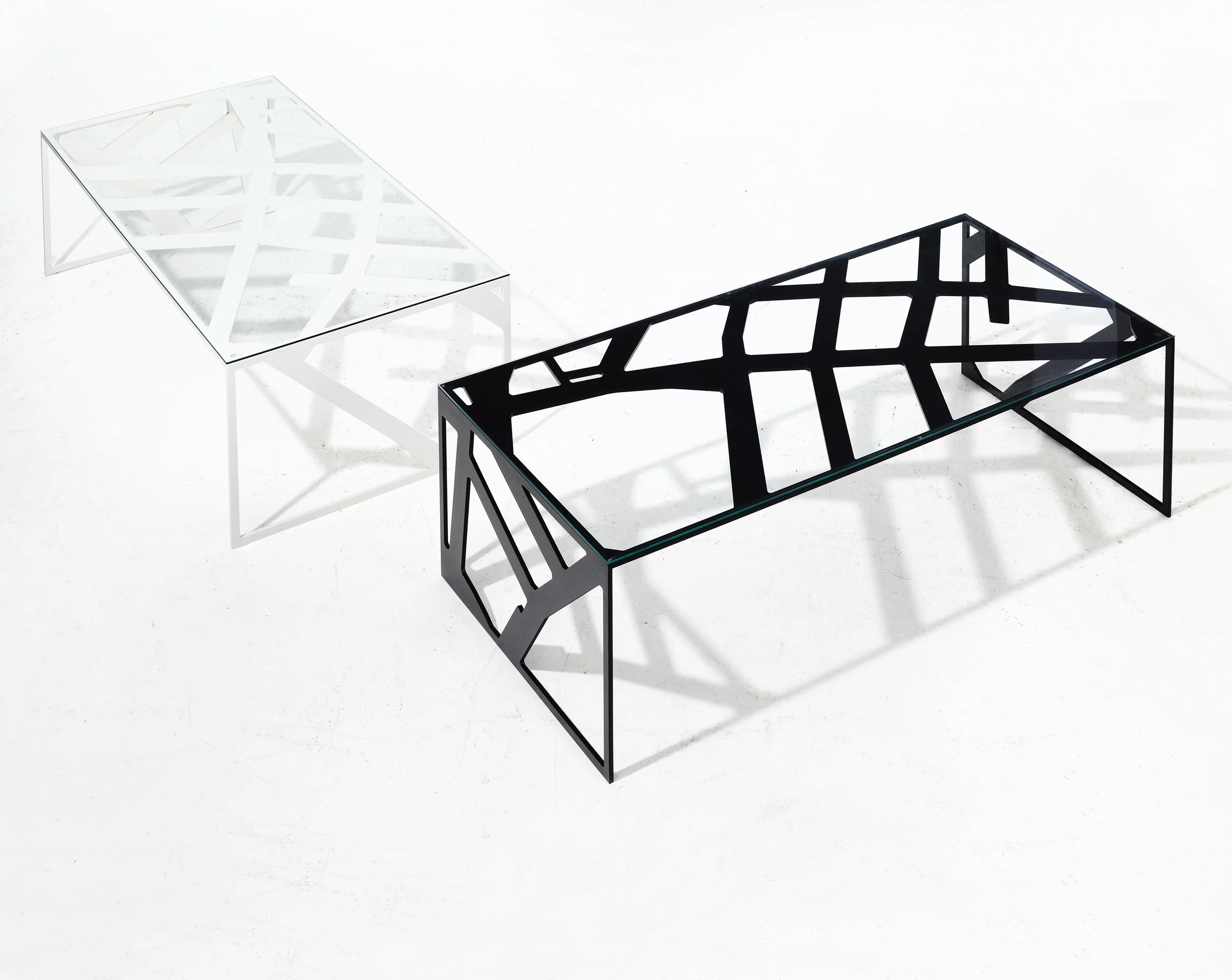 Two modern coffee tables with geometric openwork frames, one in white and one in black, and glass tops, set against a white background.