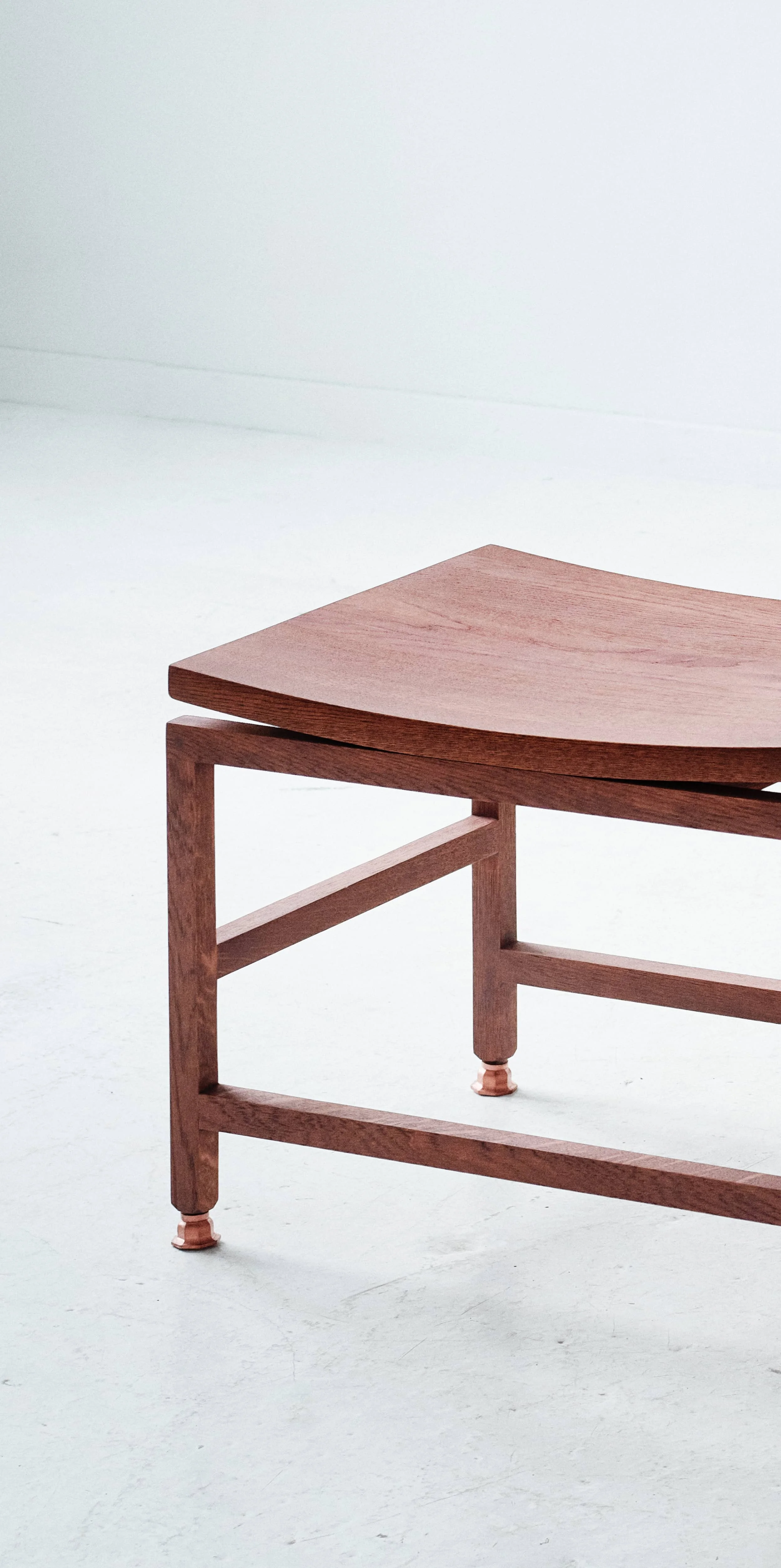 Partial view of the Kronborg Bench / Kronborg bænken with a curved seat and four legs, set against a plain white background.