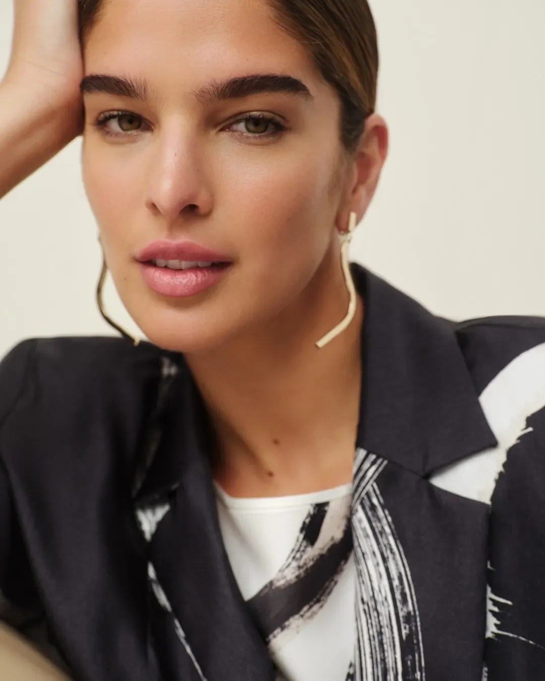 Momento di retropalco e beauty nel backstage Marina Rinaldi: la makeup artist applica il rossetto alla modella che indossa l'abito nero monospalla con dettagli oro