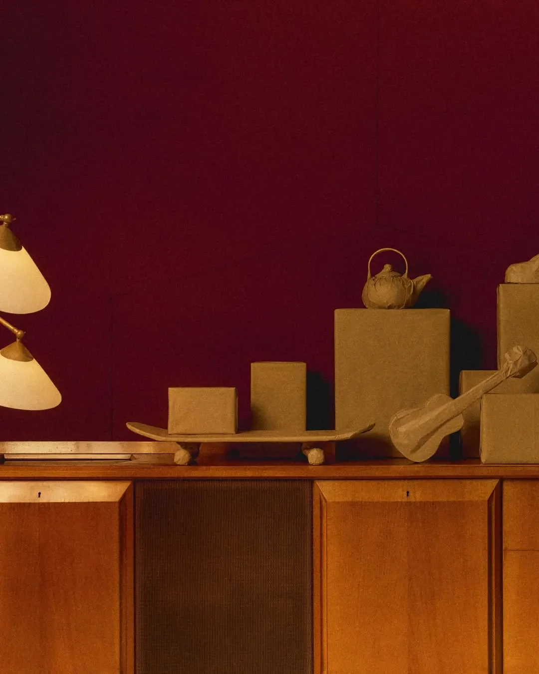 Allestimento scenografico e props design per campagna pubblicitaria Hogan. Elementi e pacchi avvolti in carta da imballo vintage posizionati su arredo in legno e luce calda.